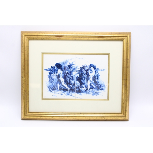 45 - A pair of Delft style tiles depicting two cherubs in gilt frame, 24cm x 17cm.