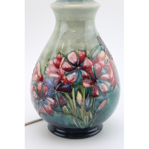307 - Moorcroft lampbase with floral decoration on green background, 20cm tall.