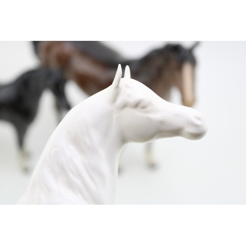 21 - Three Beswick horses to inclue a brown swishtail, an overpainted 'opaque' Arab Xayal and a black / b... 