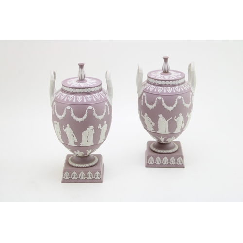 An impressive pair of Wedgwood lilac jasperware twin handled pedestal urns and covers, decorated in relief with classical figures and swags, height 23cm (2).