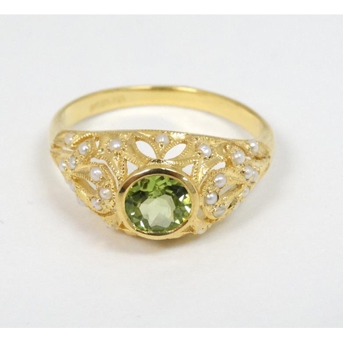 1006 - A silver gilt ring set with central peridot set with numerous seed pearls to the openwork mount