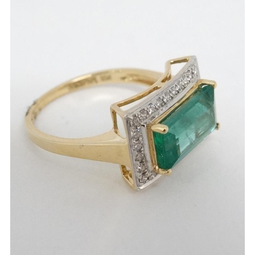 1012 - An 18ct gold ring set with central emerald bordered by diamonds.