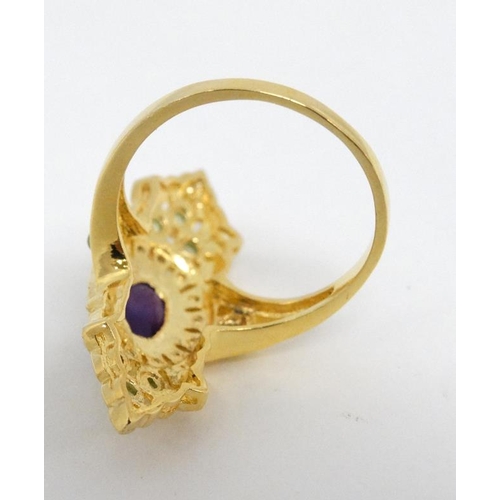 1014 - A silver gilt ring set with amethyst cabochon to centre  and a profusion of peridot and seed pearls ... 