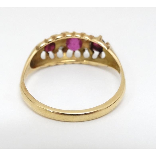 1024 - An 18ct gold ring set with central ruby flanked by 2 garnets and white stones