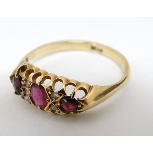 1024 - An 18ct gold ring set with central ruby flanked by 2 garnets and white stones