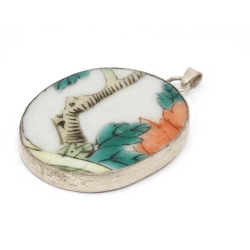 1031 - A pendant set with Oriental hand painted ceramic panel within a white metal mount. 1 ½'' long