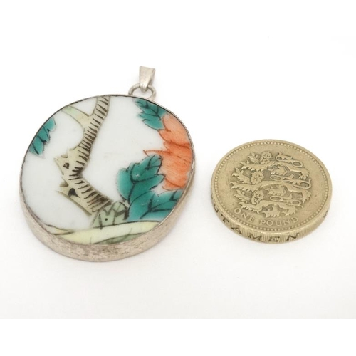 1031 - A pendant set with Oriental hand painted ceramic panel within a white metal mount. 1 ½'' long