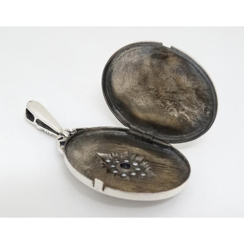 1040 - A silver locket of oval form set with seed pearls and amethyst. Marked Sterling. Approx 2'' long