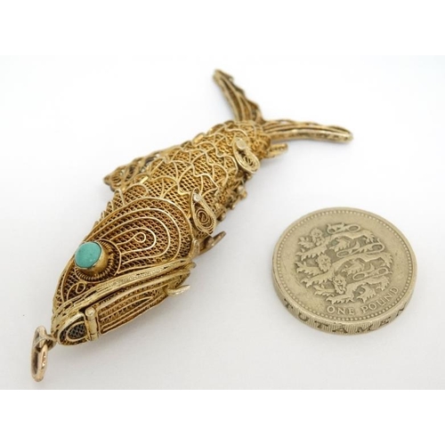 1041 - A silver gilt pendant / vinaigrette formed as an articulated fish set with turquoise cabochon. 2 ¾''... 