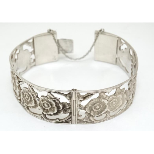 1055 - A Continental .800 silver bangle with open work floral decoration.