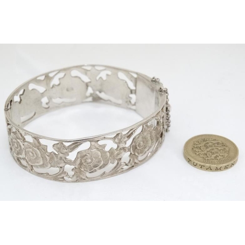 1055 - A Continental .800 silver bangle with open work floral decoration.