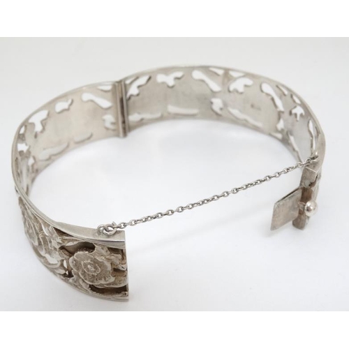 1055 - A Continental .800 silver bangle with open work floral decoration.