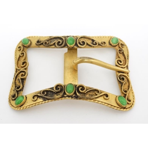 1056 - A gilt metal buckle with scroll decoration and set with 6 green stone cabochon. 3'' wide