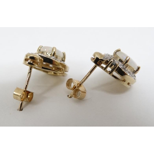 1057 - A pair of 9ct gold earrings set with opals, white stones and green stone. Approx. ½'' long