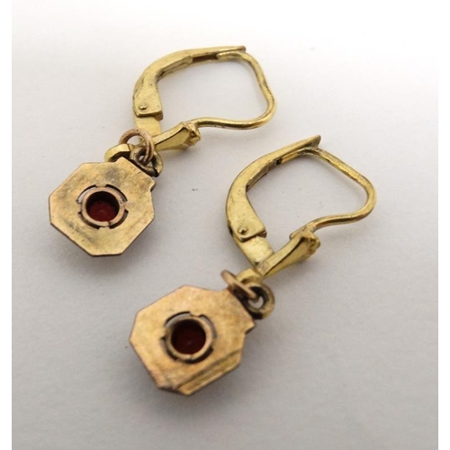 1065 - A pair of gilt metal earrings set with red stones