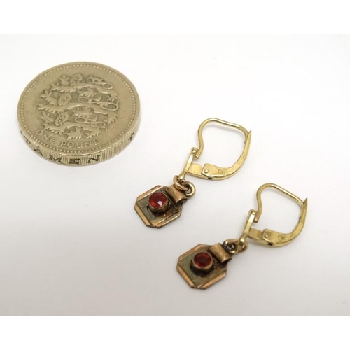 1065 - A pair of gilt metal earrings set with red stones