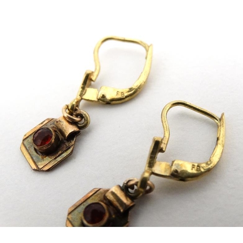 1065 - A pair of gilt metal earrings set with red stones