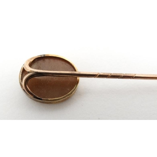 1066 - A gilt metal stick pin surmounted by a classical cameo.