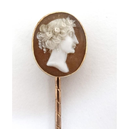 1066 - A gilt metal stick pin surmounted by a classical cameo.