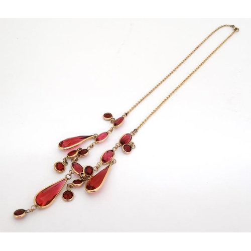 1067 - A gilt metal necklace set with facet cut pink/red stones. Approx. 17'' long