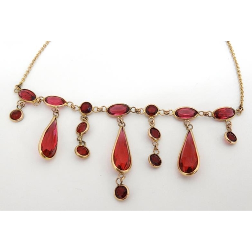 1067 - A gilt metal necklace set with facet cut pink/red stones. Approx. 17'' long