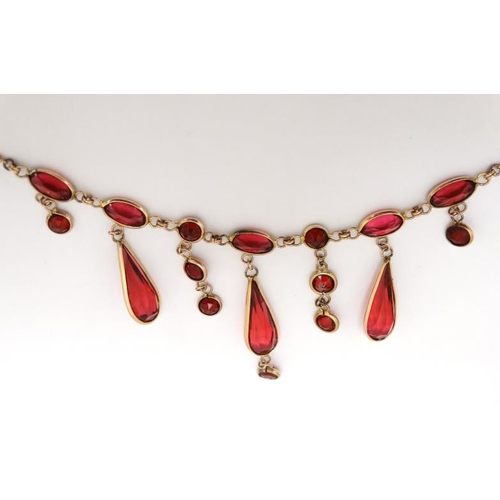 1067 - A gilt metal necklace set with facet cut pink/red stones. Approx. 17'' long