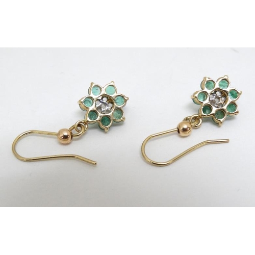 1069 - A pair of yellow metal drop earrings set with emeralds.