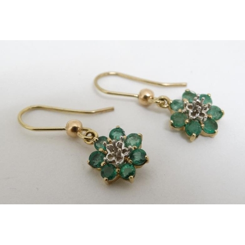 1069 - A pair of yellow metal drop earrings set with emeralds.