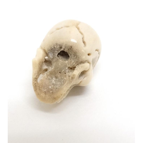 1085 - A carved bone ojimie bead formed as a human skull ¾'' high