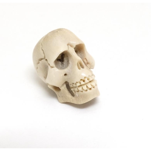 1085 - A carved bone ojimie bead formed as a human skull ¾'' high