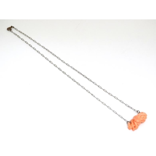 1088 - A white metal chain set with carved coral? Pendant of floral form. Approx 20'' long