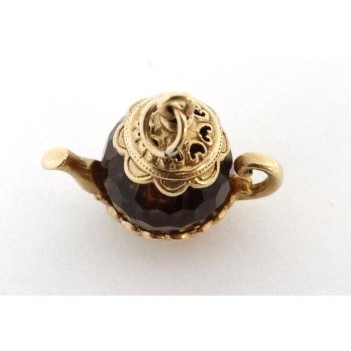 1091 - A pendant / charm formed as a miniature teapot the facet amber coloured body with yellow metal mount... 