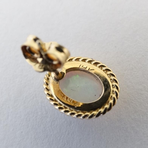 1104 - A pair of 9ct gold stud earrings set with opal cabochon with rope twist mounts.