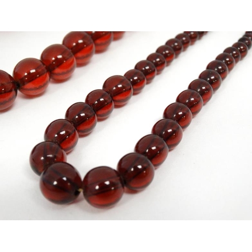 1122 - 2 Vintage necklaces of graduated cherry amber coloured beads. 20'' long and 17'' long