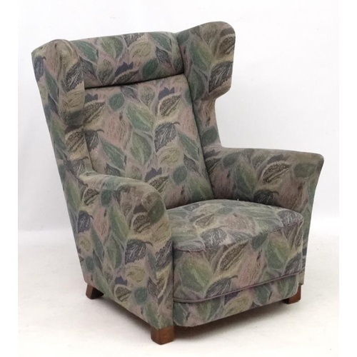 142 - Vintage Retro : A Danish upholstered wing back  armchair with show wood feet, 38 1/2'' high