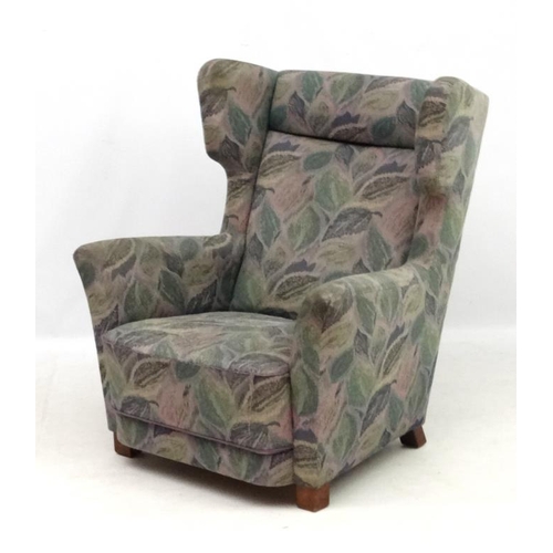 142 - Vintage Retro : A Danish upholstered wing back  armchair with show wood feet, 38 1/2'' high