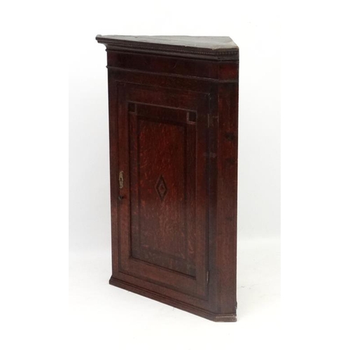 214 - A Georgian Oak hanging corner cupboard  with single panelled inlaid and crossbanded door opening to ... 