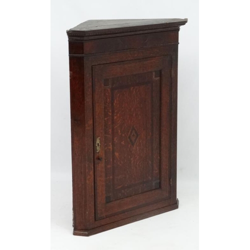 214 - A Georgian Oak hanging corner cupboard  with single panelled inlaid and crossbanded door opening to ... 