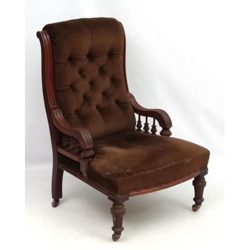 310 - A late 19thC mahogany elbow chair with button back upholstery and fluted and turned front legs. 37''... 