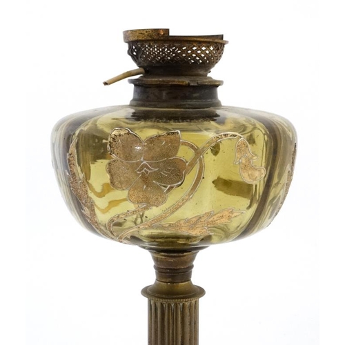 322 - An unusual oil lamp with reeded column, circular base and gilt with tube lined enamel amber coloured... 