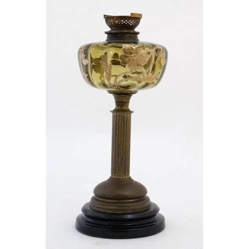 322 - An unusual oil lamp with reeded column, circular base and gilt with tube lined enamel amber coloured... 