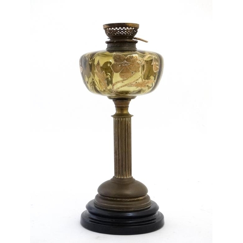 322 - An unusual oil lamp with reeded column, circular base and gilt with tube lined enamel amber coloured... 