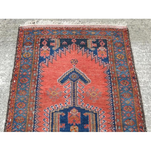 54 - Carpet / Rug : A woollen rug with blue and red/pink ground with geometric arrow like motifs 81'' x 4... 