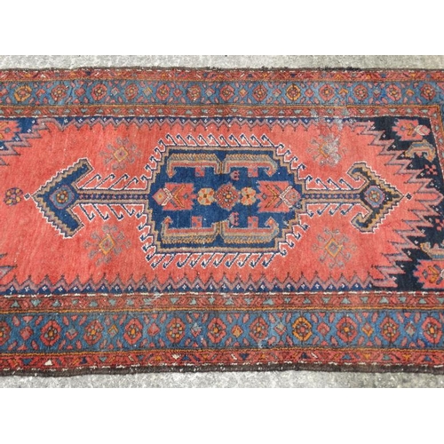 54 - Carpet / Rug : A woollen rug with blue and red/pink ground with geometric arrow like motifs 81'' x 4... 