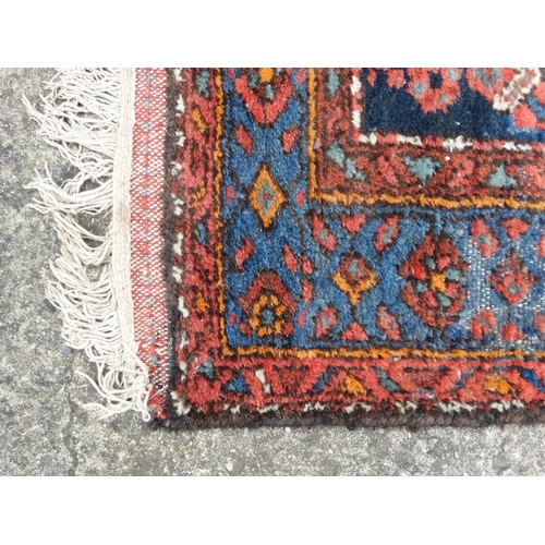 54 - Carpet / Rug : A woollen rug with blue and red/pink ground with geometric arrow like motifs 81'' x 4... 