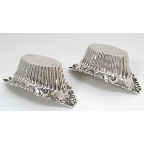 553 - A pair of silver salts of boat form with fluted sides and C scroll border. Hallmarked Birmingham 190... 