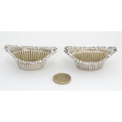 553 - A pair of silver salts of boat form with fluted sides and C scroll border. Hallmarked Birmingham 190... 