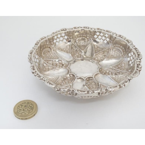 558 - A silver bon bon dish of circular form with embossed and pierced decoration on 3 ball feet hallmarke... 