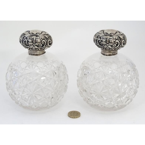 597 - A pair of cut glass scent bottle of spherical form with silver tops hallmarked Chester 1904 maker Wi... 