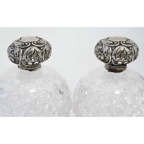 597 - A pair of cut glass scent bottle of spherical form with silver tops hallmarked Chester 1904 maker Wi... 